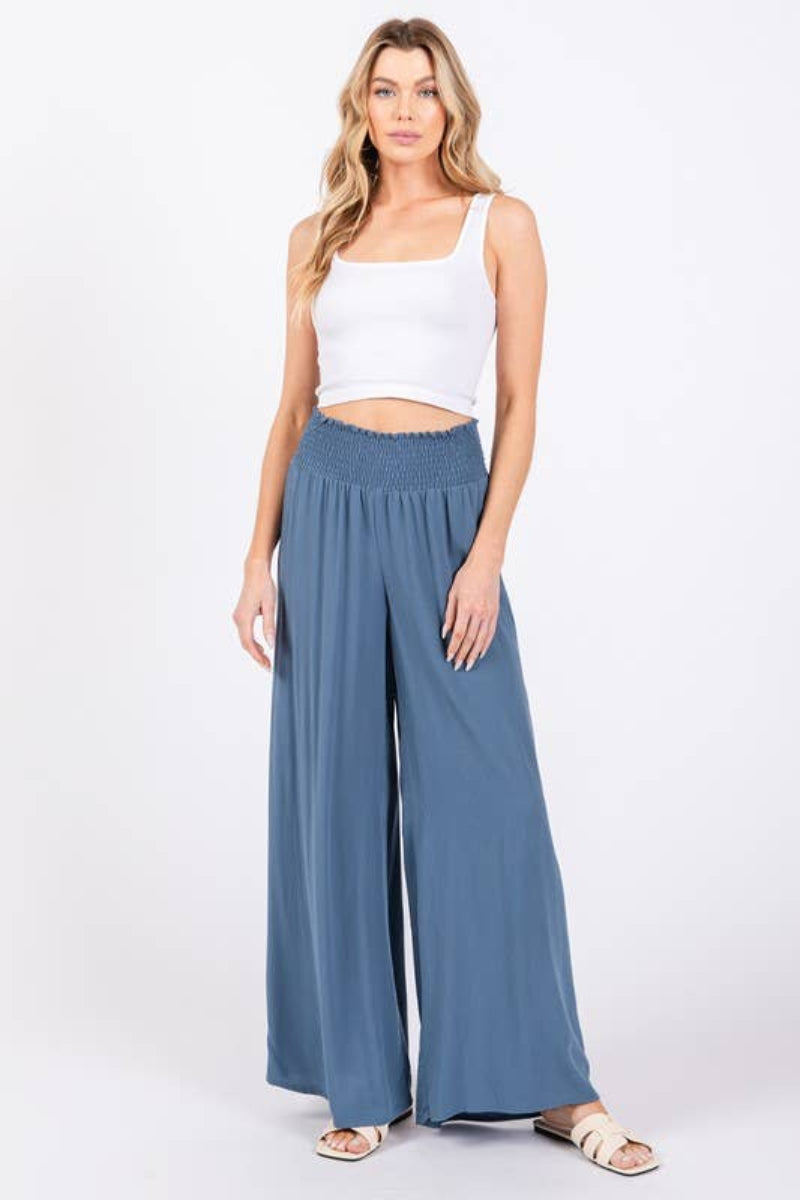 Woman wearing a white top and blue wide-leg pants on a white background
