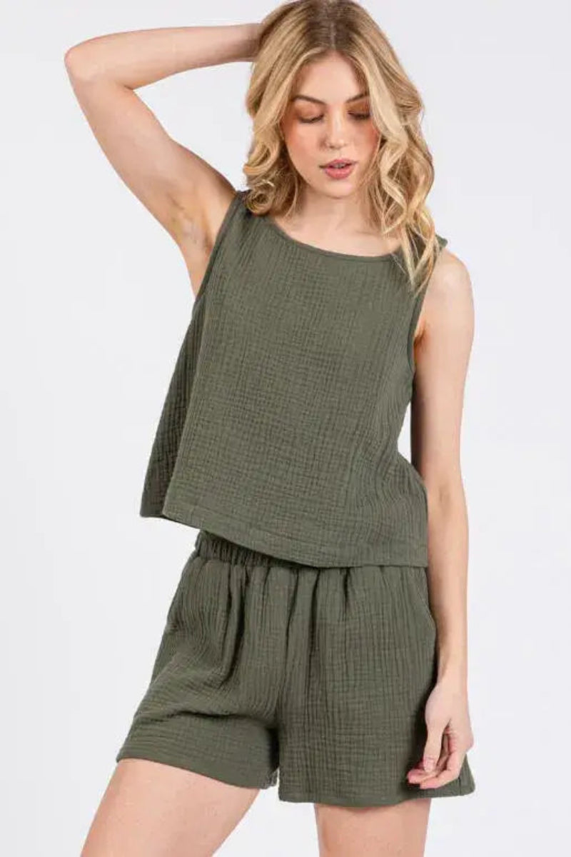 Woman wearing an olive green sleeveless top and shorts set on a white background