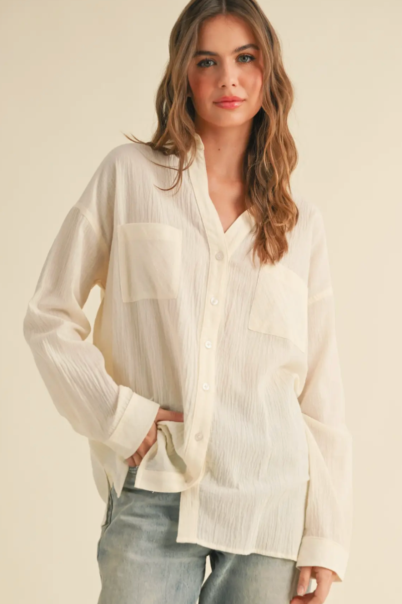 Woman wearing a light-colored blouse with a neutral background