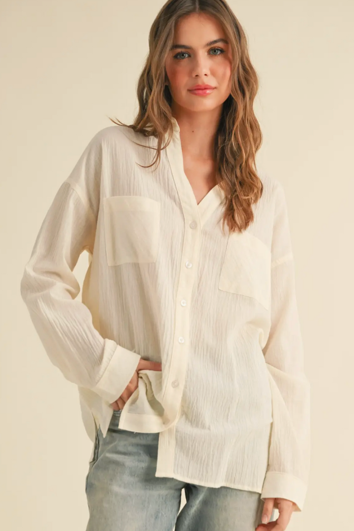 Woman wearing a light-colored blouse with a neutral background