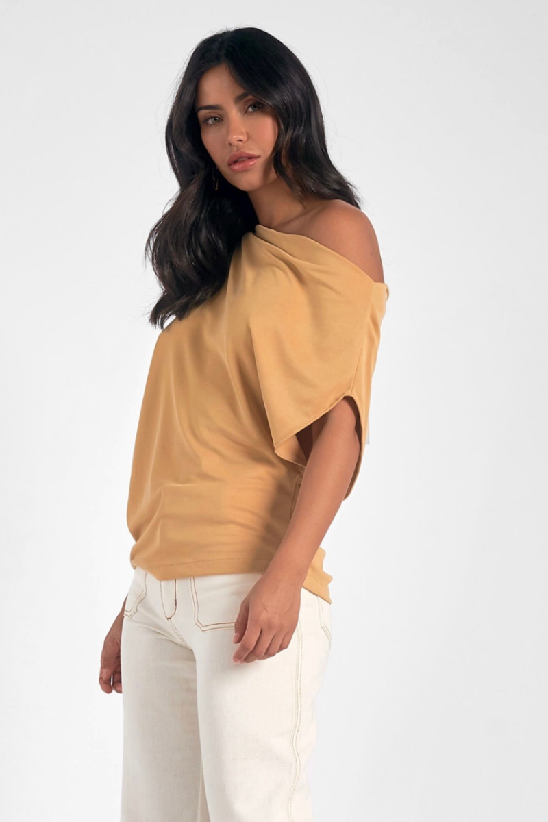 Woman wearing a mustard yellow off-shoulder top and white pants on a white background