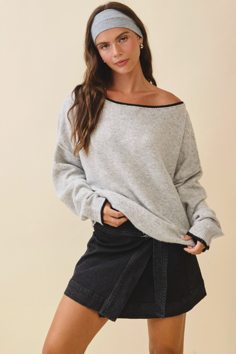 Woman wearing a gray sweater and black skirt on a beige background