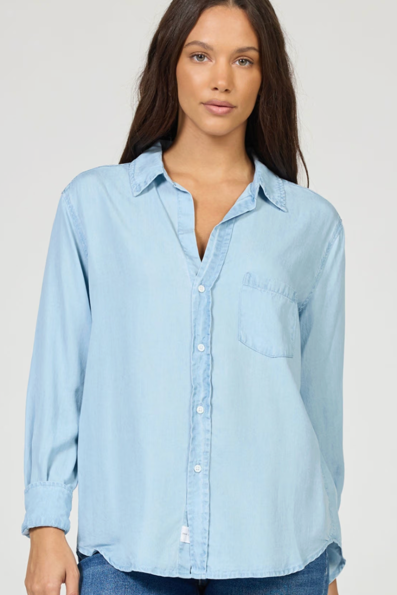 Woman wearing a light blue tencel shirt against a plain background