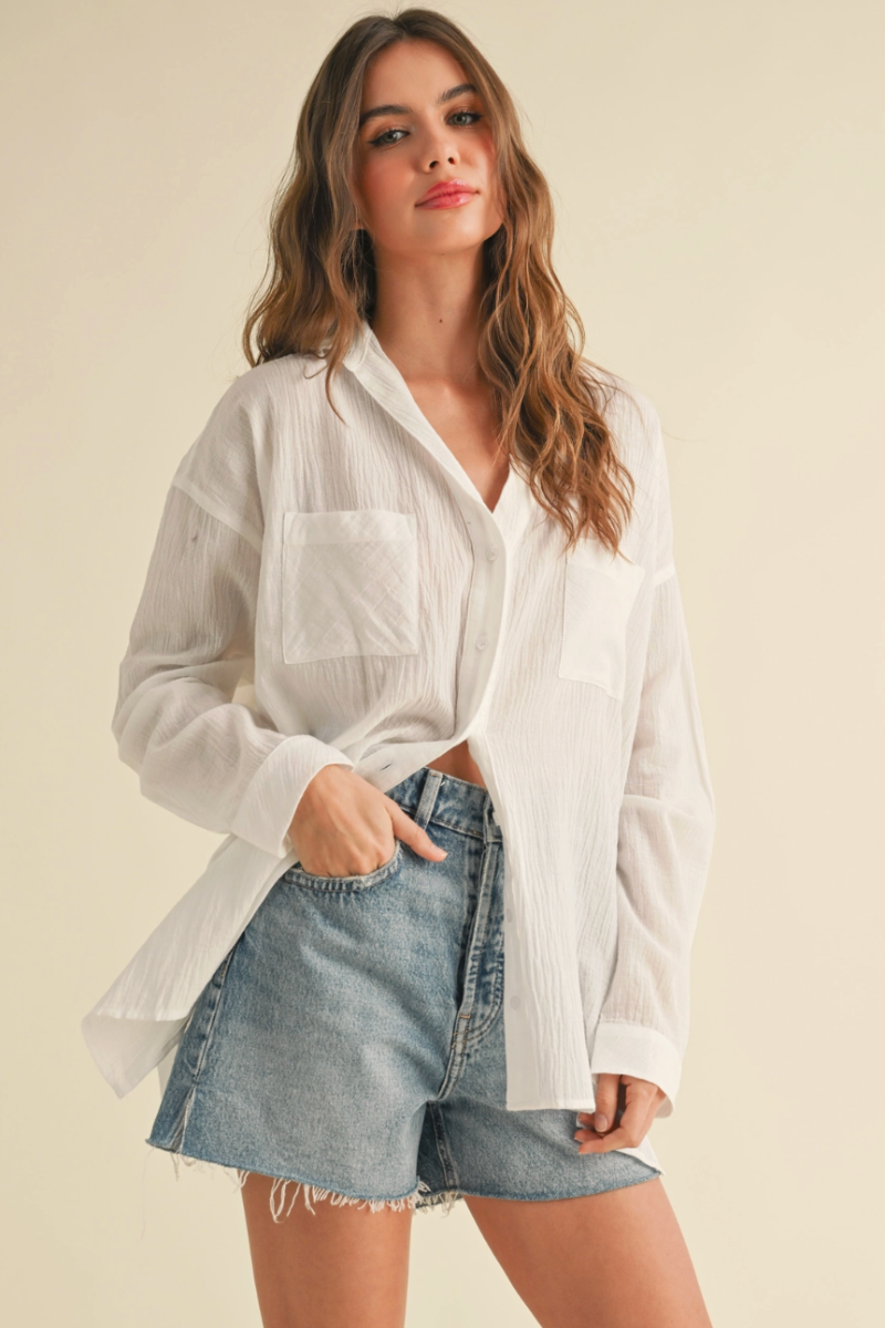 Woman wearing a white shirt and denim shorts on a beige background
