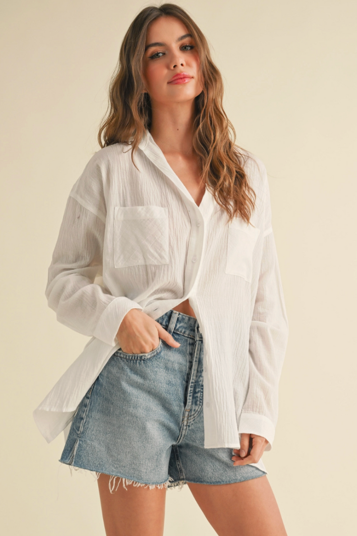 Woman wearing a white shirt and denim shorts on a beige background