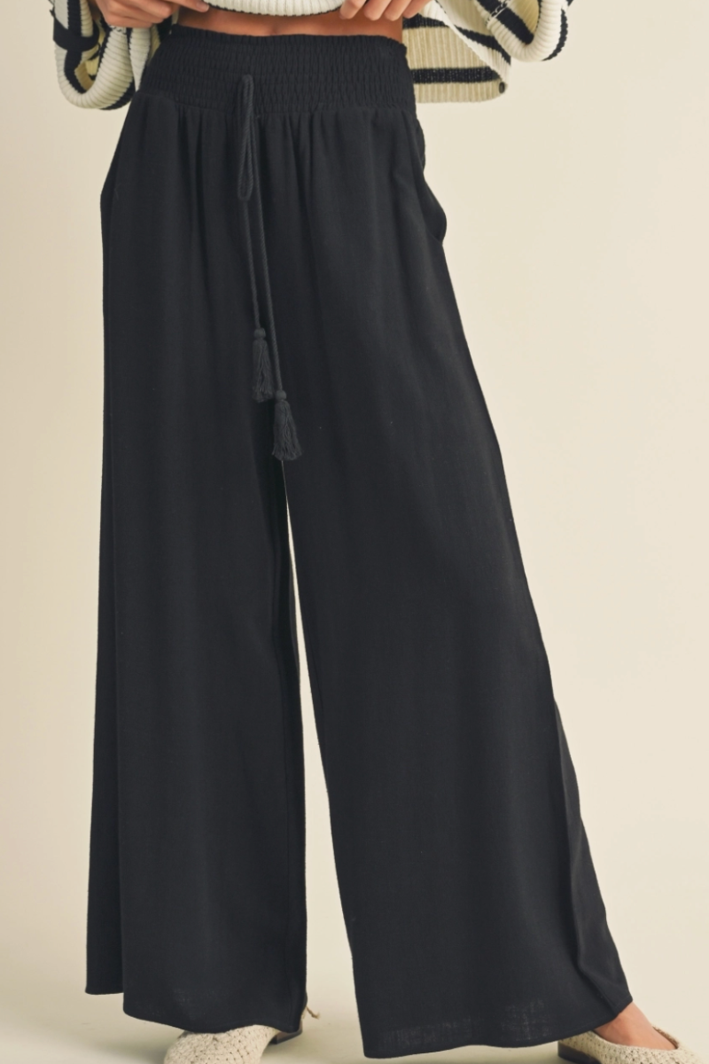 Black wide-leg pants worn by a person on a beige background