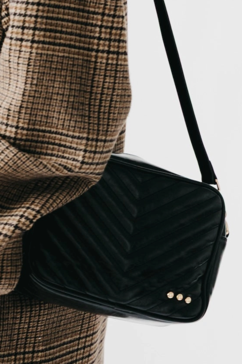 Black handbag with gold studs on a white background