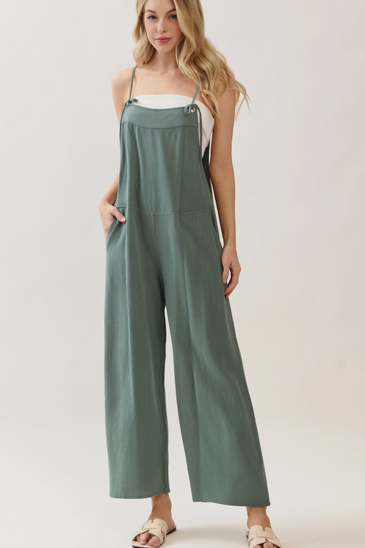 Woman wearing a green jumpsuit on a plain background